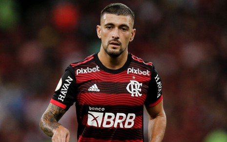Arrascaeta, do Flamengo, veste uniforme listrado em vermelho e preto durante partida da equipe
