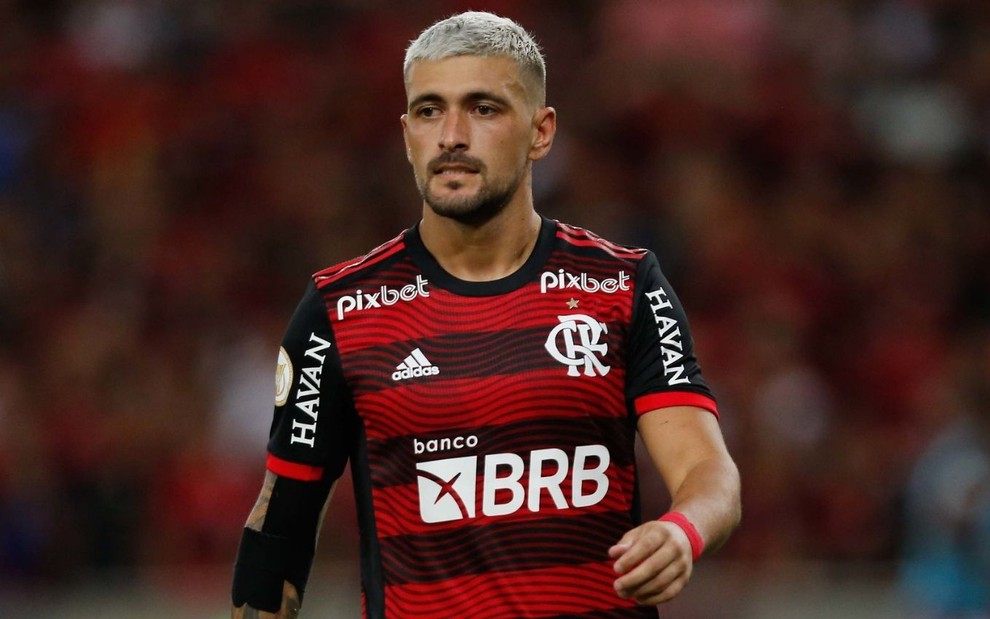 Jogador Arrascaeta, do Flamengo, veste uniforme listrado em vermelho e preto durante partida