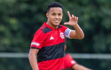 Jogador Lázaro, do Flamengo, veste uniforme vermelho com listras pretas e comemora gol em partida
