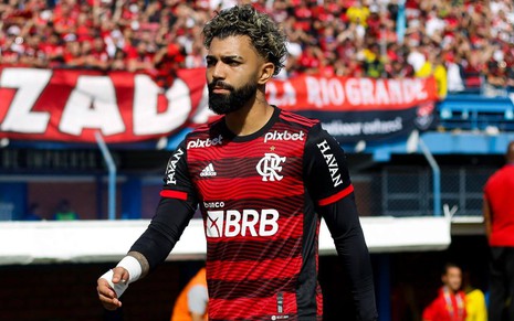 Gabigol, do Flamengo, caminha em campo e veste uniforme listrado em vermelho e preto