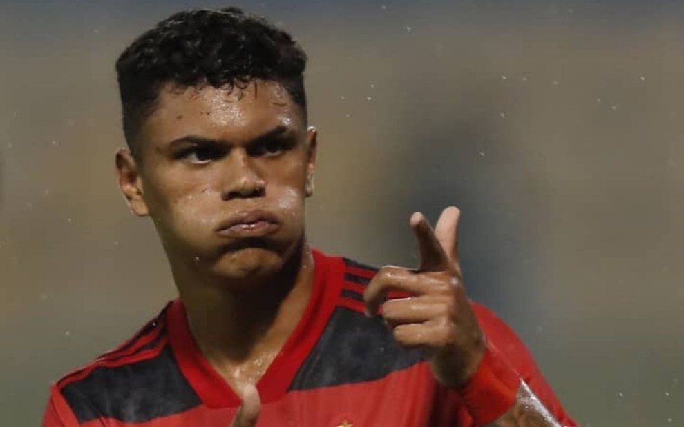 Jogador Mateusão, do Flamengo, veste uniforme vermelho com listras pretas e comemora gol em partida