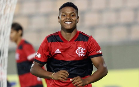 Jogador Matheus França, do Flamengo, veste uniforme vermelho com listras pretas e comemora gol feito