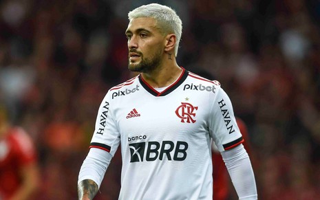 Arrascaeta, do Flamengo, caminha em campo e veste uniforme branco com detalhes vermelhos e pretos