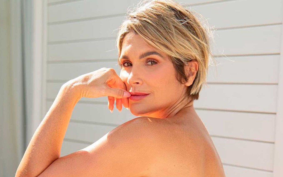 A atriz Flávia Alessandra está com o torso nu, de perfil, e leva a mão ao queixo em clique de seu instagram