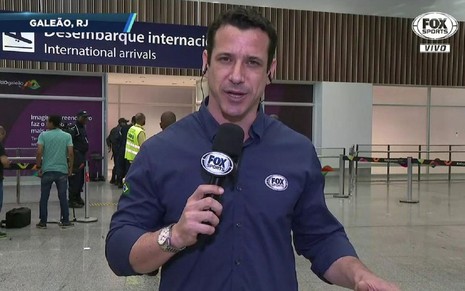 Flávio Winicki com a camisa azul e microfone do Fox Sports, no aeroporto do Galeão, no Rio de Janeiro