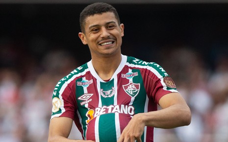 André, do Fluminense, comemora gol com bola debaixo da camiseta listrada em grená, verde e branco