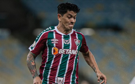Atacante Cano, do Fluminense, corre em campo e veste uniforme listrado em grená, verde e branco