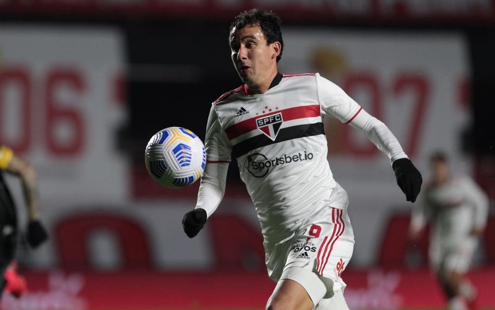 O jogador de futebol Pablo em jogo do São Paulo Futebol Clube com a bola no ar prestes a ser chutada