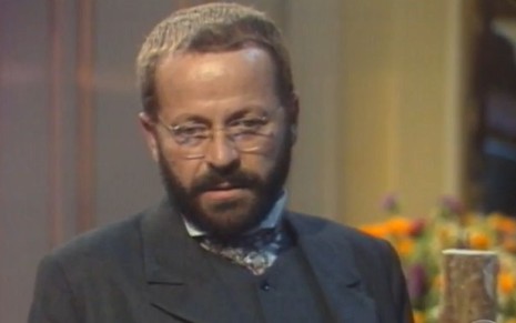 Carlos Vereza usa terno e óculos de grau e está com expressão séria em cena como Francisco Monserrat na novela Direito de Amar