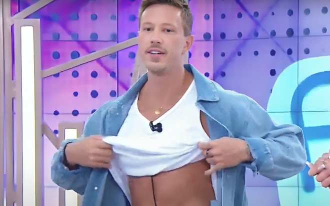 Gabriel Cartolano está com parte da blusa erguida, no Fofocalizando, no SBT