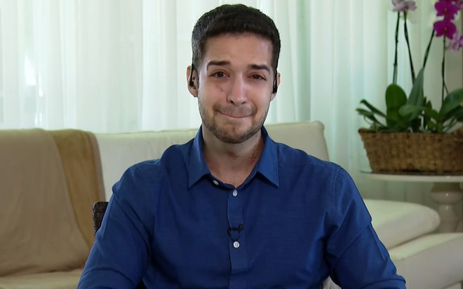 Gabriel Luiz no Encontro desta segunda-feira (9); ele está em sua casa via vídeoconferência, veste uma camisa azul e está chorando