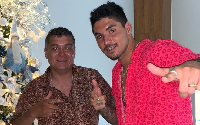 Cláudio Ferreira (à esquerda) faz sinal positivo com as mãos; Gabriel Medina (à direita) sorri
