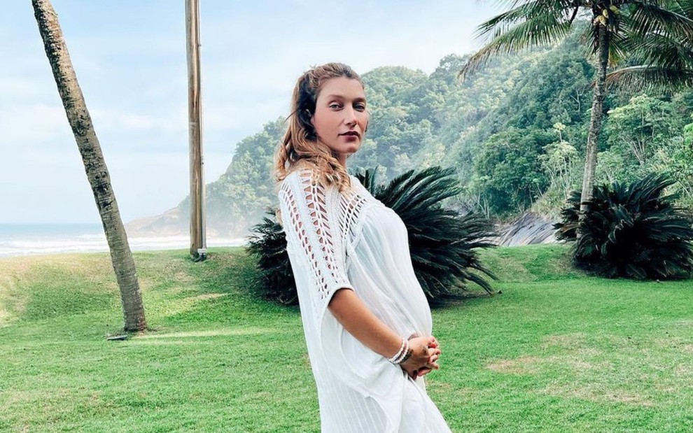 Influenciadora digital Gabriela Pugliesi de túnica branca em foto na praia