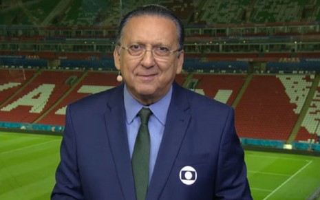 Galvão Bueno com um terno azul, gravata verde em uma transmissão da Globo