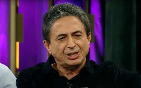 O repórter Gerson de Souza em entrevista a Fábio Porchat; ao fundo, cenário roxo