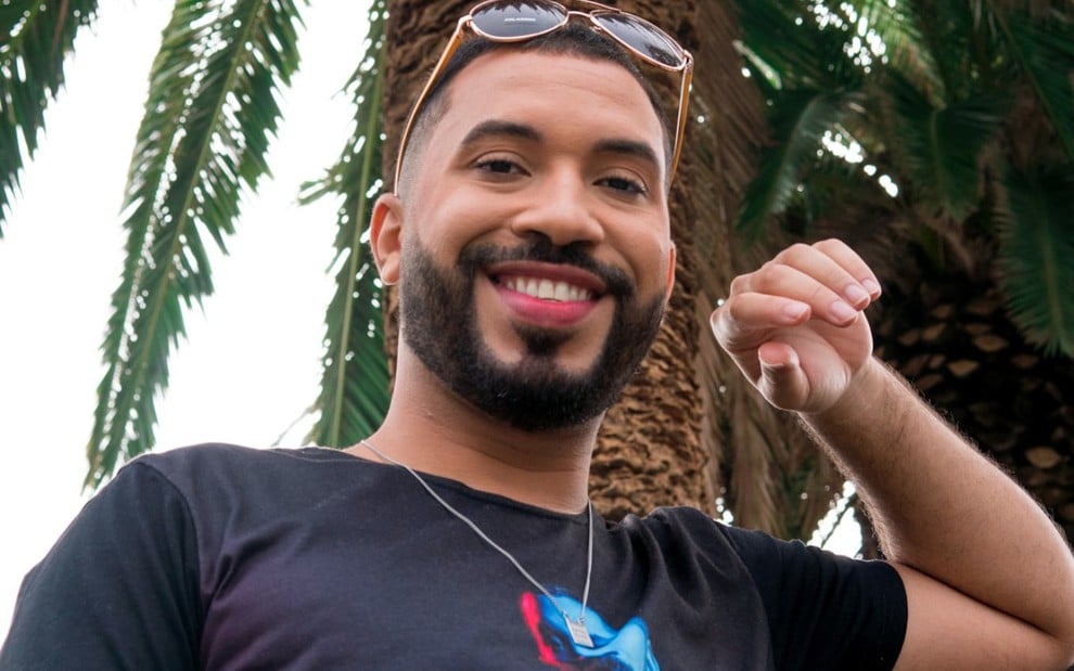 Gilberto Nogueira com sorriso, óculos escuros na cabeça, olha para a câmera em cena externa do documentário Gil na Califórnia