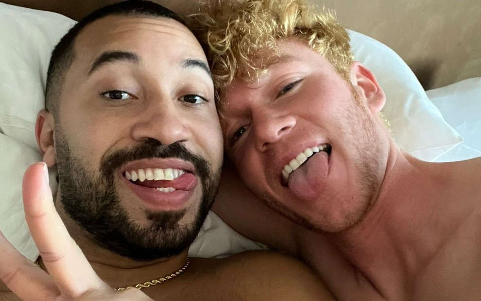 Gil do Vigor e um rapaz loiro deitados na cama sem camisa posando para uma foto publicada no Twitter do ex-BBB