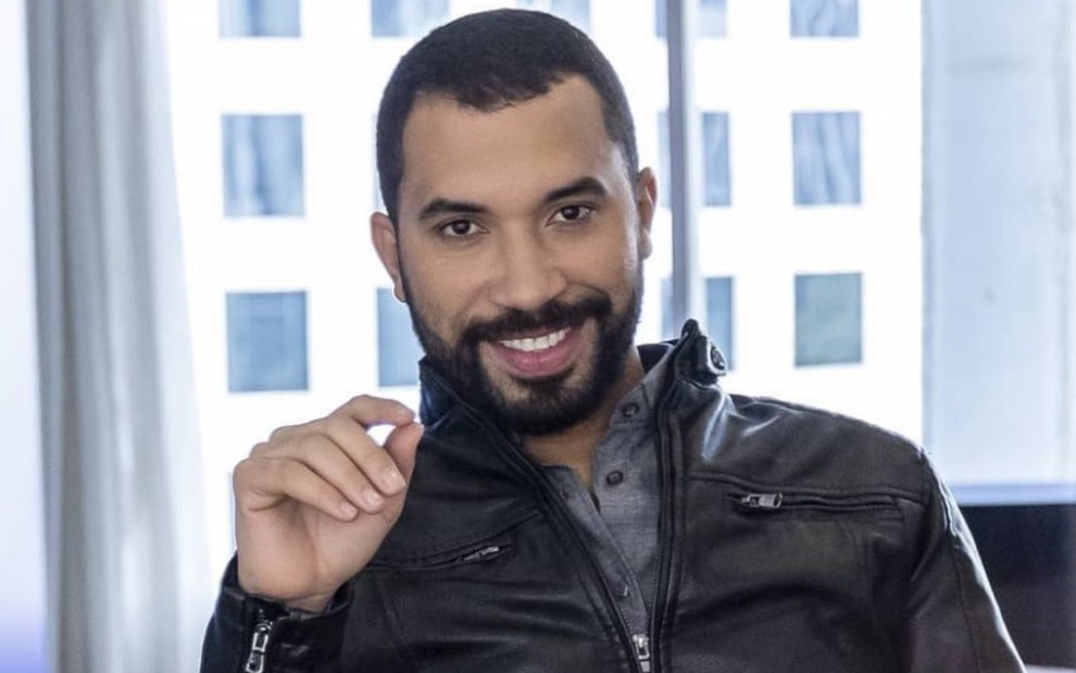 Gilberto Nogueira, o Gil do Vigor, posa sorridente para foto; ele está com uma jaqueta preta
