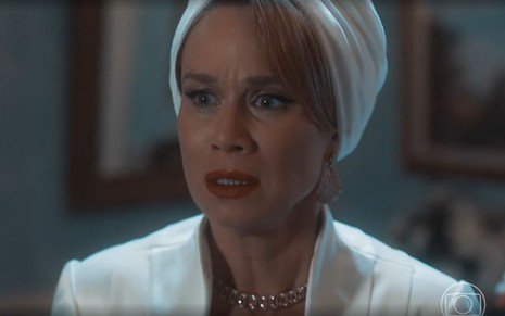 Em cena de Amor Perfeito, Mariana Ximenes veste roupa e turbante branco e está com a expressão de susto