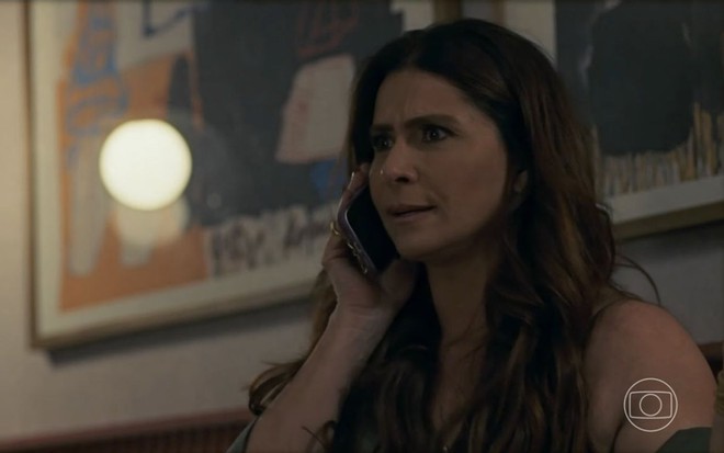 Em cena de Travessia, Giovanna Antonelli, com os cabelos soltos, está falando ao celular, parecendo estar nervosa