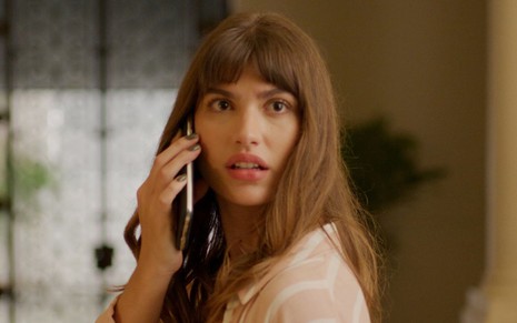 Giovanna Grigio está com o celular no ouvido e faz cara de espanto em cena do filme Perdida