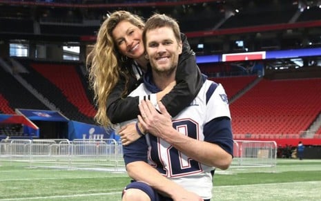 Imagem de Gisele Bündchen abraçando Tom Brady em um campo de futebol americano