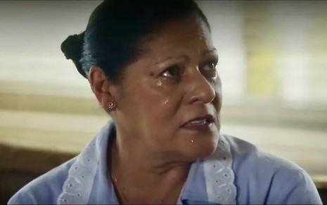 A atriz Luci Pereira está chorando com uniforme de empregada em cena da novela Travessia como Creusa