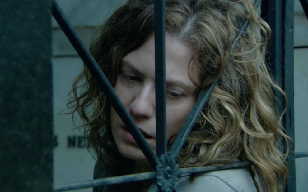 Patricia Pillar, a Flora, tem a expressão perturbada; ela está encostada nas grades de um mausoléu em cena de A Favorita