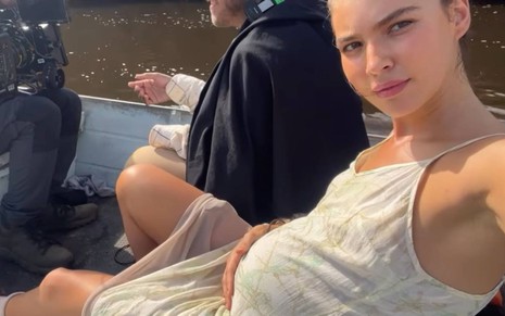Atriz Alanis Guillen segura barriga de grávida e olha para câmera dentro de um barco no Pantanal