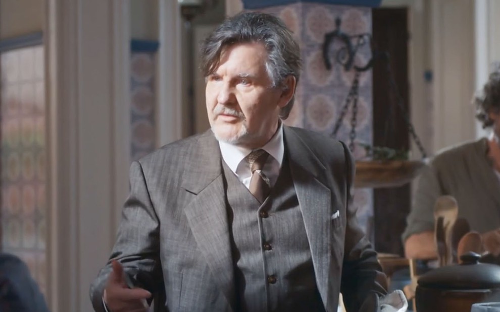 O ator Antonio Calloni caracterizado como Matias em uma cozinha em cena de Além da Ilusão