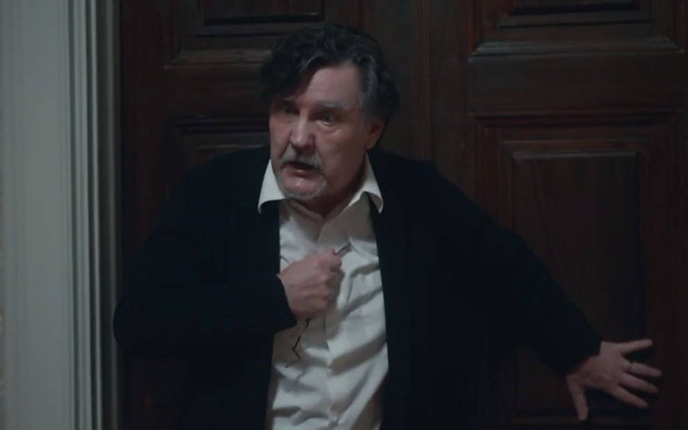 Matias (Antonio Calloni) está encostado em porta em cena de Além da Ilusão, novela das seis