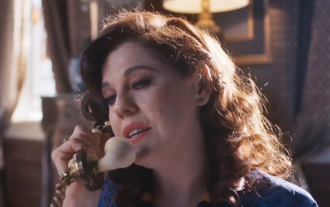 Bárbara Paz grava cena com expressão séria ao telefone, como Úrsula em Além da Ilusão