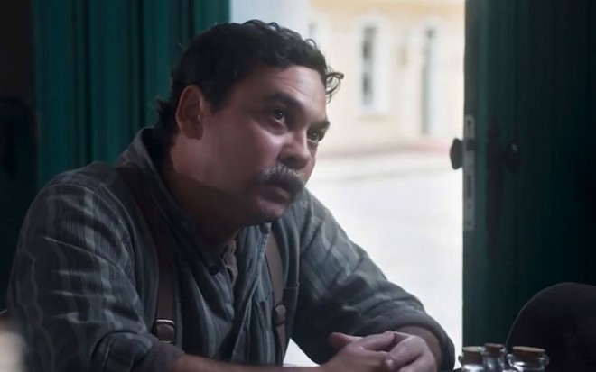 Cipriano (Cláudio Gabriel) está sentado, pensativo, em cena de Além da Ilusão