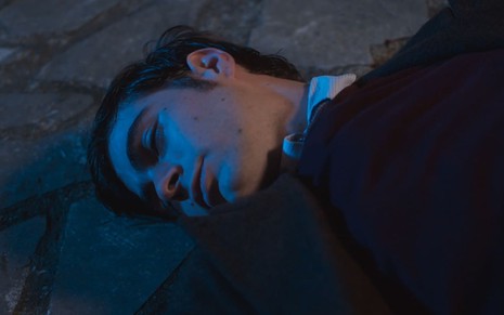 Rafael Vitti, caracterizado como Davi, está desmaiado no chão em cena de Além da Ilusão