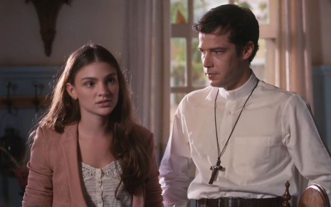 Debora Ozório grava cena com expressão séria ao lado de Jayme Matarazzo, como Olívia e padre Tenório