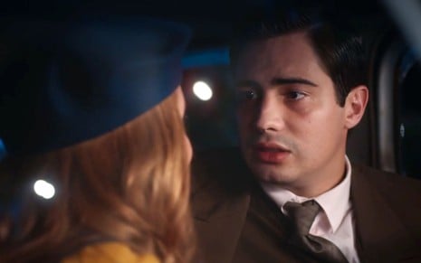 Danilo Mesquita em cena de Além da Ilusão: ator está sentado dentro do carro e olha para Larissa Manoela, que está de costas para a câmera