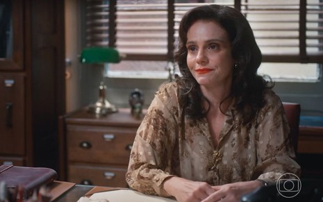 Violeta (Malu Galli) está sentada em escritório em cena de Além da Ilusão, novela das seis da Globo
