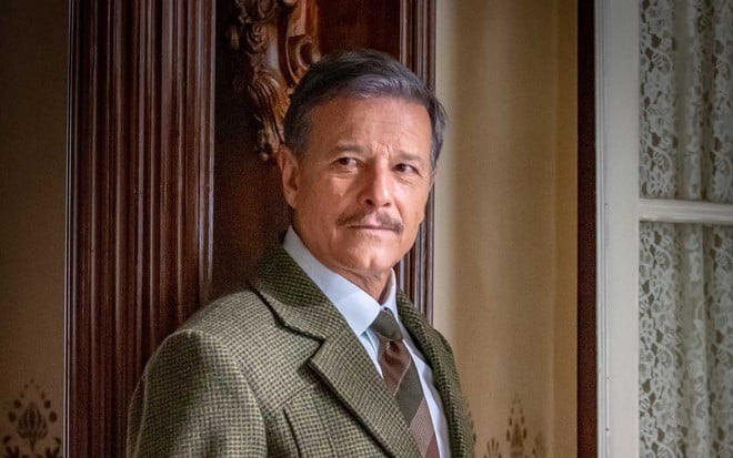 O ator Marcello Novaes de terno cinza e caracterizado como Eugênio em cena de Além da Ilusão