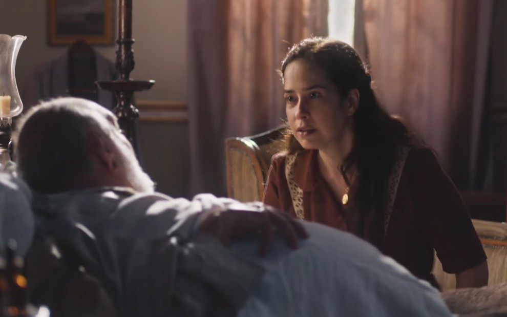 A atriz Paloma Duarte, ajoealhada diante de uma cama em que Lima Duarte está como o coronel Afonso, com expressão de raiva como a Heloísa em cena de Além da Ilusão