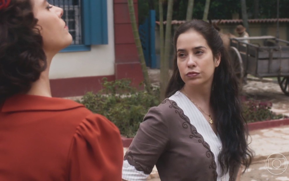 A atriz Paloma Duarte caracterizada como Violeta em cena de Alem da Ilusão olha para Malu Galli, que quase não aparece na imagem