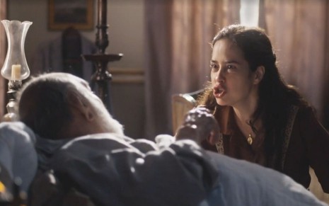Heloísa (Paloma Duarte) está revoltada, e Afonso (Lima Duarte) deitado em cama em cena de Além da Ilusão