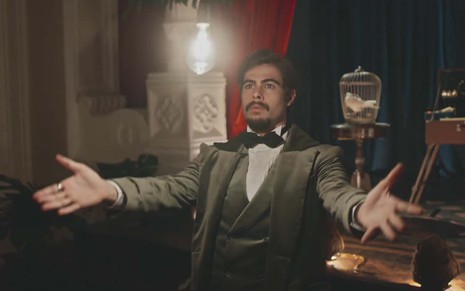 O ator Rafael Vitti, com um smoking, faz uma lâmpada levitar como o Davi em cena de Além da Ilusão