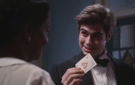Davi/Rafael (Rafael Vitti) segura carta de baralho na mão em cena de Além da Ilusão, novela das seis da Globo
