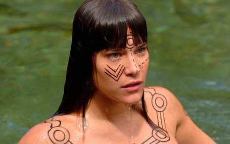 A atriz Priscila Fantin, com pinturas indígenas no corpo, dentro de um lago de águas cristalinas como a Serena em cena de Alma Gêmea