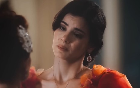 Camila Queiroz usa um vestido azul escuro; ela tem o semblante sério e choroso em teaser de Amor Perfeito