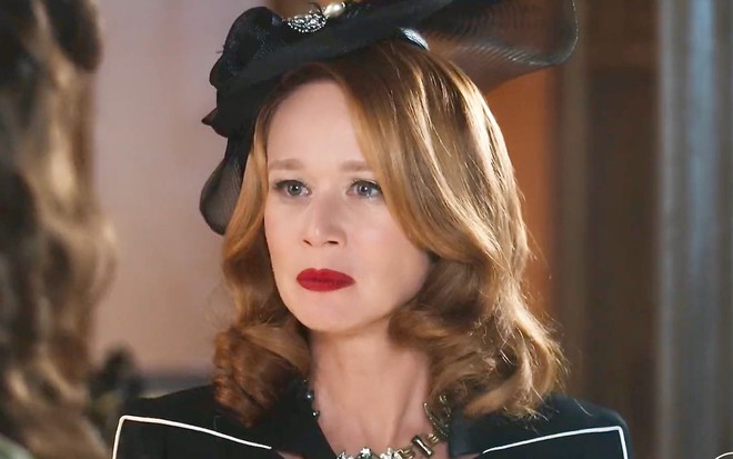 Mariana Ximenes está com chapéu preto e batom vermelho em cena da novela Amor Perfeito como Gilda