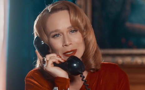 A atriz Mariana Ximenes usa blusa vinho e fala ao telefone em cena de Amor Perfeito como Gilda