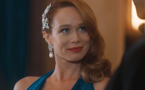 Mariana Ximenes caracterizada como Gilda; ela usa uma maquiagem bem marcada e um vestido azul escuro com transparência em cena de Amor Perfeito
