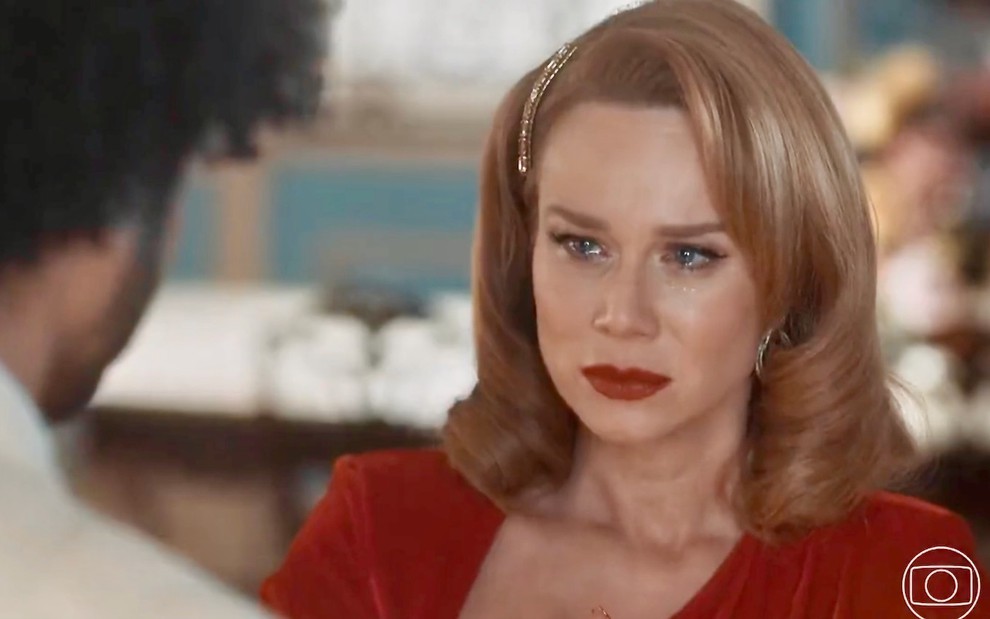 A atriz Mariana Ximenes usa vestido vermelho e tem os olhos cheios de lágrimas em cena de Amor Perfeito como Gilda