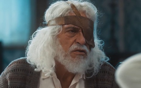Paulo Gorgulho caracterizado como Leonel; ele está com a barba longa e os cabelos despenteados em cena da novela. O semblante exprime confusão.